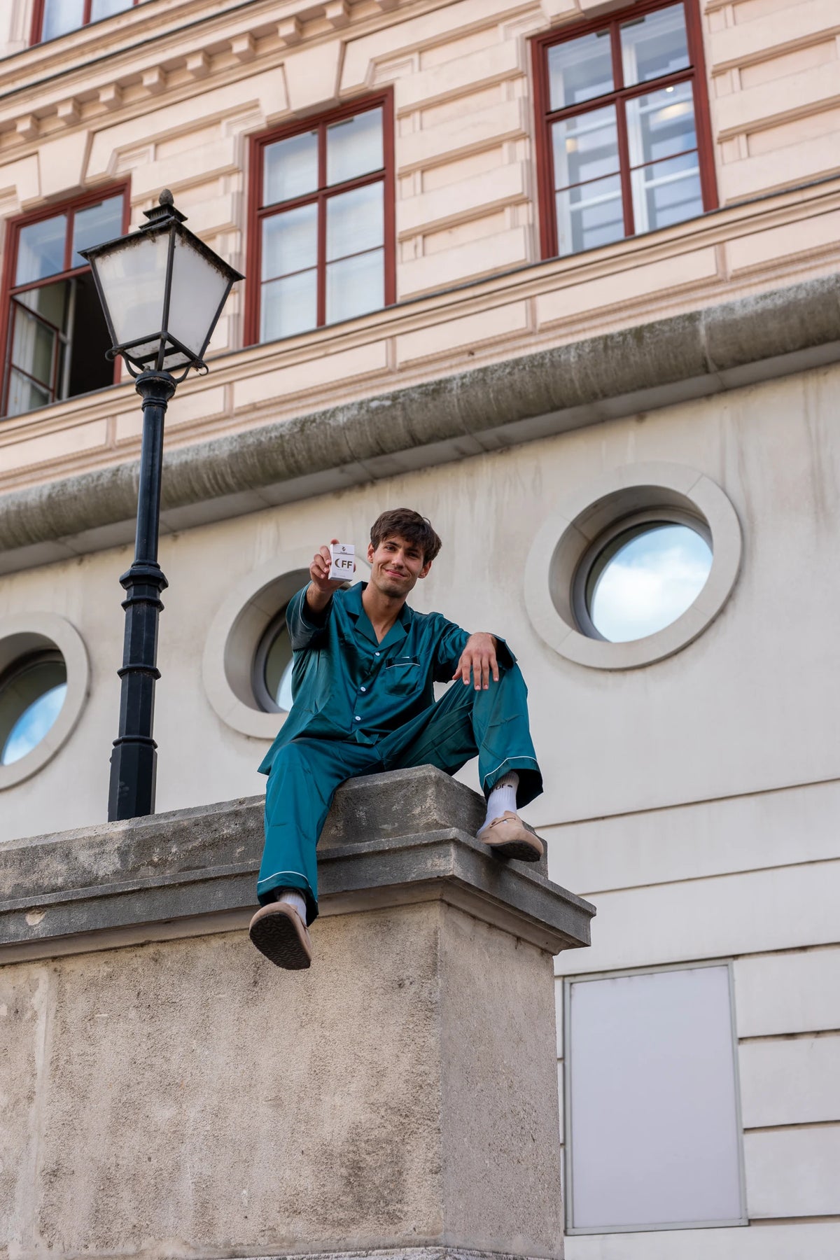 Oli in Moodsup Nightwear sitting on a wall in Vienna